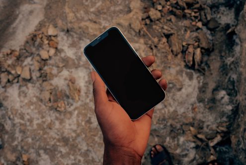 Hand holding smartphone with blank screen for mockup design on rock background, showcasing device mockup, design element for app display.